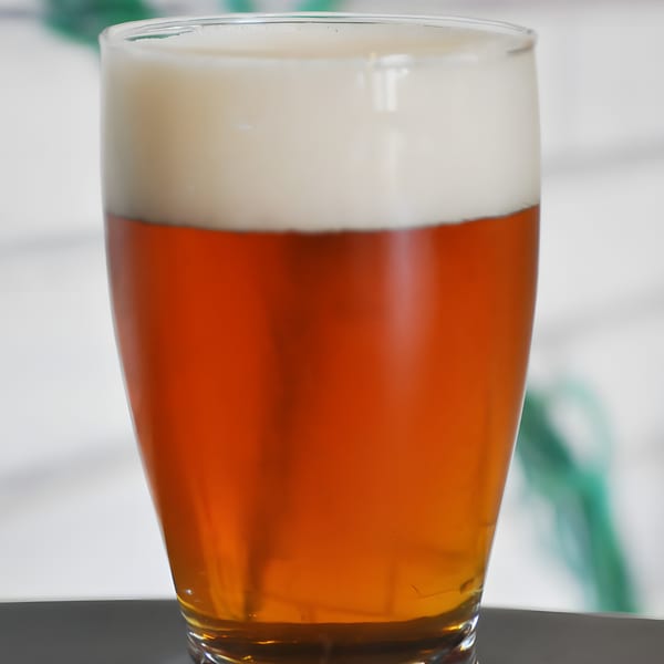 Close-up of a glass of Panzu Brewery's amber ale with a thick head of foam.