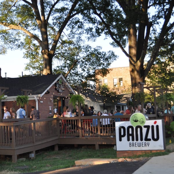 Panzu Brewery's outdoor patio with string lights, people enjoying drinks, and a large Panzu sign.