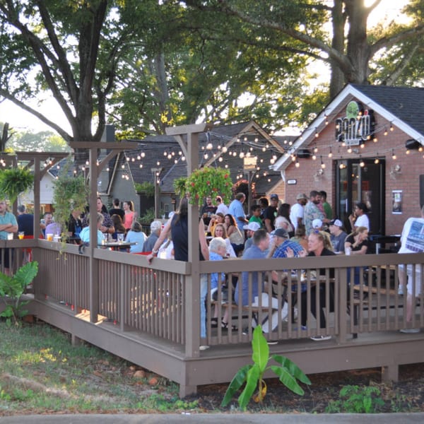 Panzu Brewery's outdoor patio is bustling with people enjoying drinks and conversation under string lights.