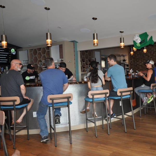 Patrons seated at the Panzu Brewery bar, with a bartender serving drinks.