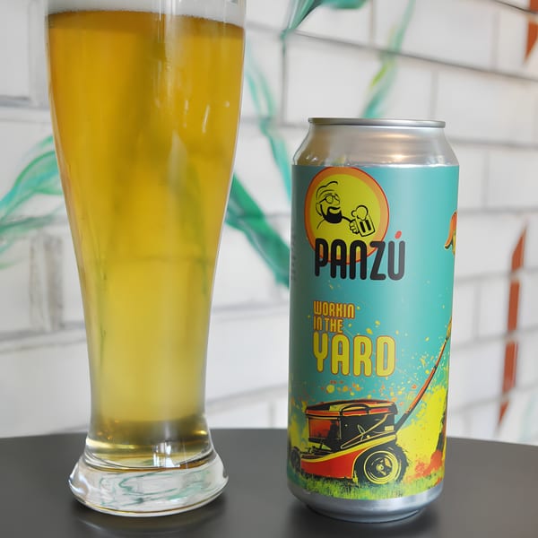 A Panzu Brewery beer can with a lawnmower graphic next to a glass of golden beer.