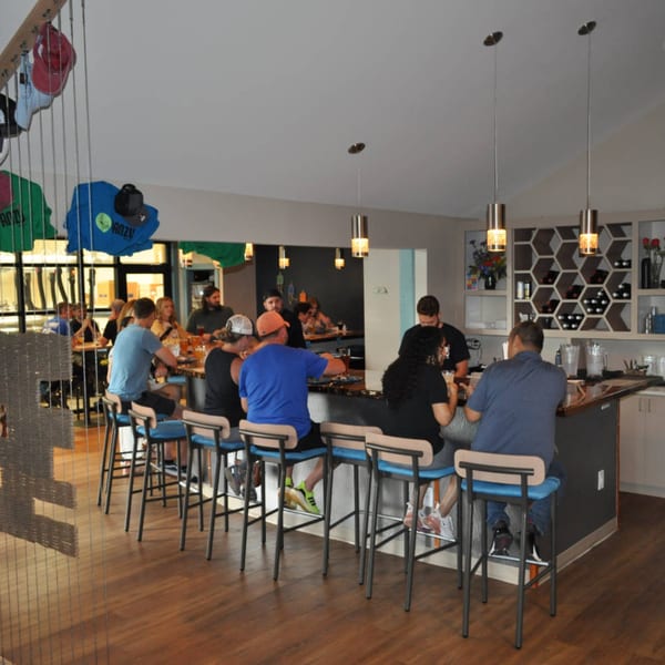 Patrons seated at a long bar inside Panzu Brewery, with staff serving drinks and food.