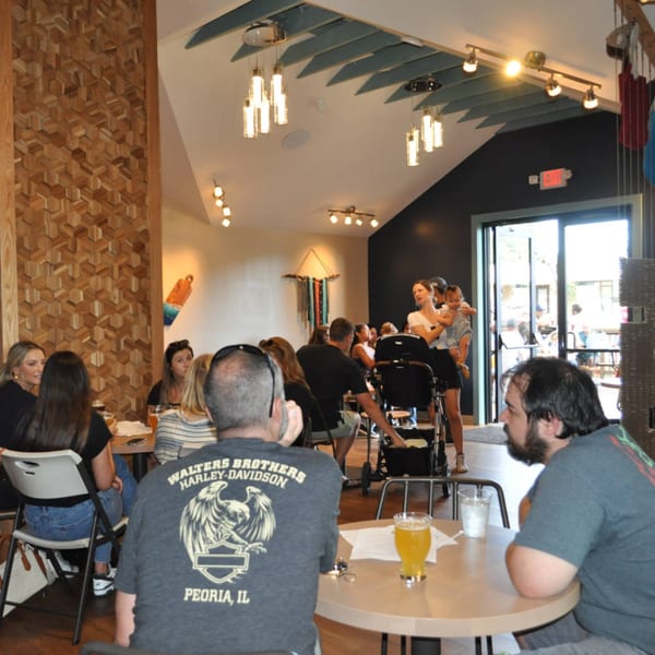 Patrons enjoying drinks and conversation inside Panzu Brewery, with a view of the outdoor patio.