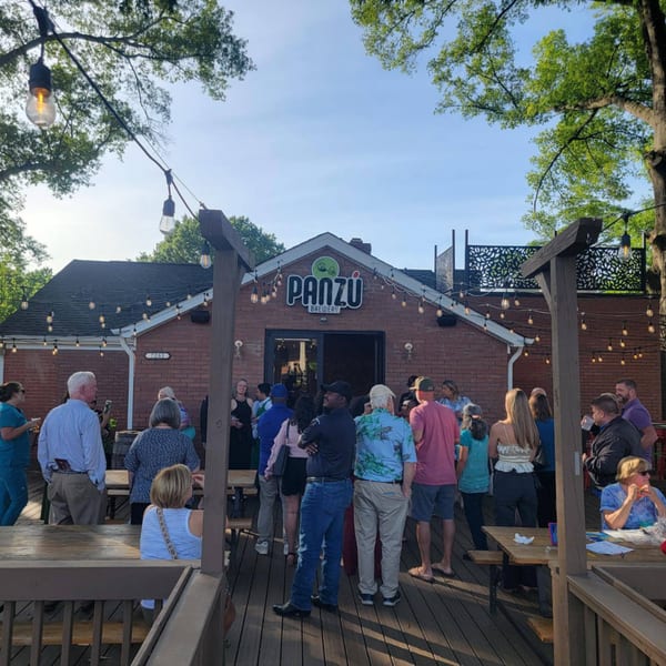 Patrons gather on the outdoor patio of Panzu Brewery, a brick building with string lights.
