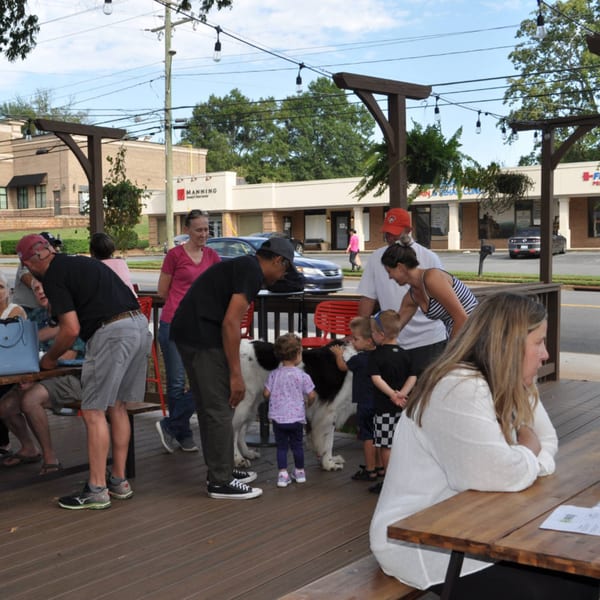 People and children interacting with a large dog on the outdoor patio of Panzu Brewery.